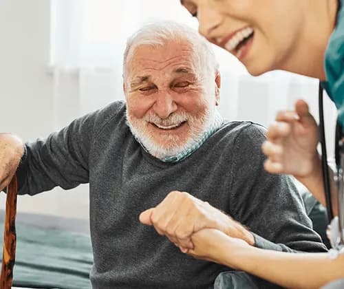A smiling older man holding hands with his carer